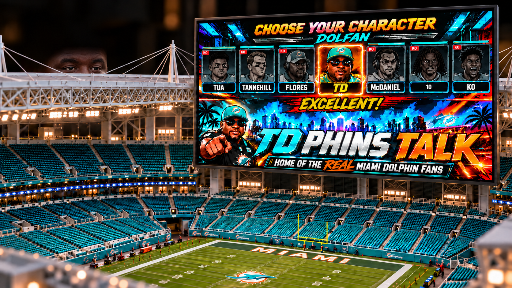 Close view of a miniature Miami football stadium and large TD Phins Talk screen, with Tony Dowe’s eyes just above the roofline