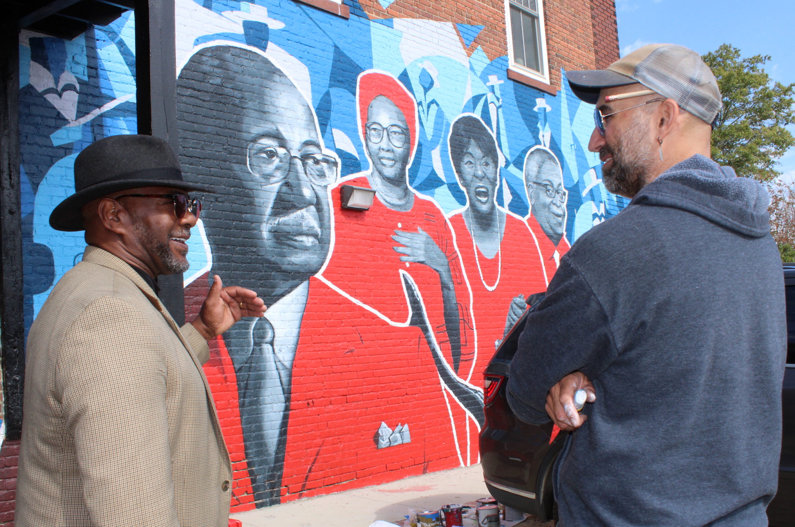 Michael Bell, left, speaks with artist Max Dowdle, right, about the African American Music Trails mural in Wilson on Tuesday. Drew C. Wilson | Times